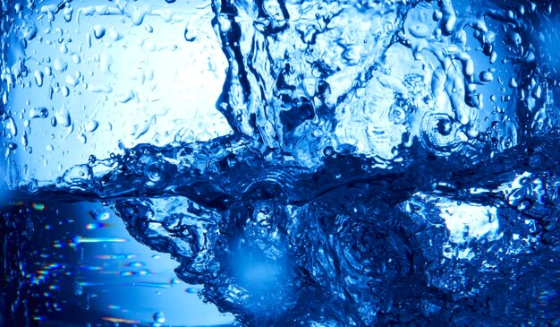 Photo gouttes d'eau tombant dans l'eau d'un bleu profond