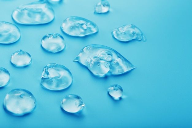 Gouttes de gel à l'acide hyaluronique sous la forme d'un frottis de texture brillante sur une surface bleue