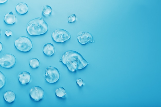 Gouttes de gel à l'acide hyaluronique sous la forme d'un frottis de texture brillante sur une surface bleue