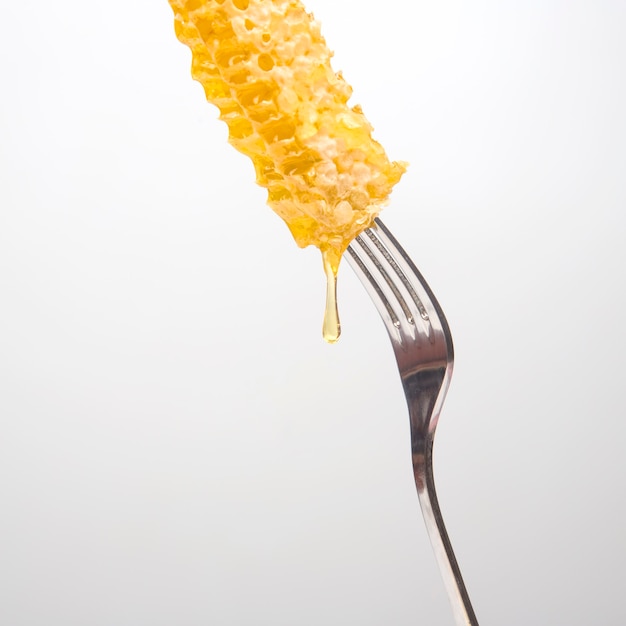 Des gouttes de miel frais coulent de miel de cire sur une fourchette de table. nutrition vitaminique et produit apicole