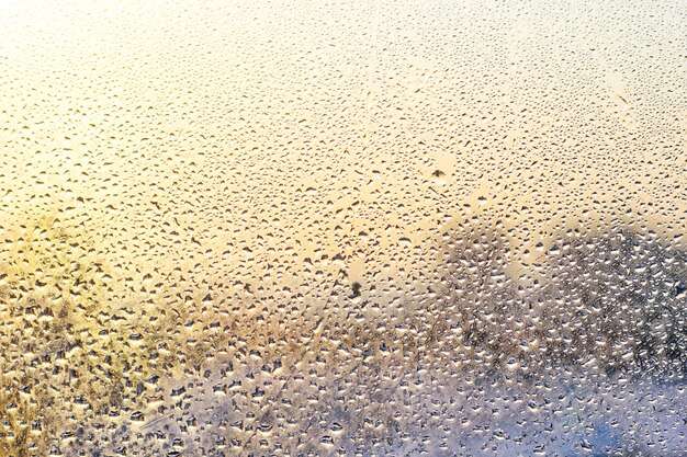 Gouttes de pluie et eau gelée sur fond de verre de fenêtre