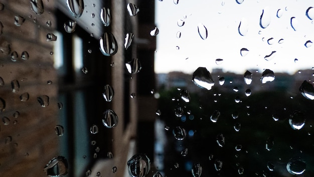 Gouttes de pluie sur la fenêtre regardant la ville de nuit