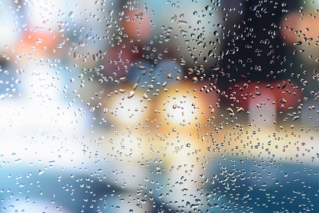 Gouttes de pluie sur une fenêtre de voiture avec un arrière-plan magnifiquement flou de feux de circulation