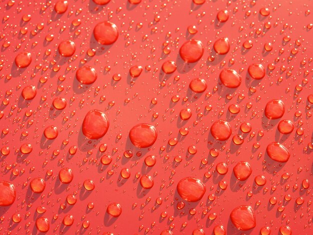 Photo gouttes de pluie formées sur une surface métallique rouge