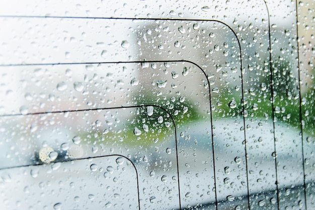 Gouttes de pluie sur la surface de la vitre de la voiture par temps de pluie avec un arrière-plan flou