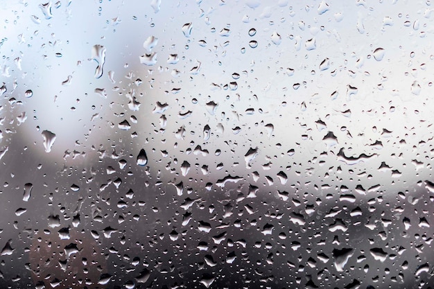 Gouttes de pluie sur verre embué dans les tons gris