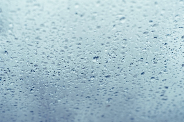 Gouttes de pluie sur verre à vitre, bleu tonique