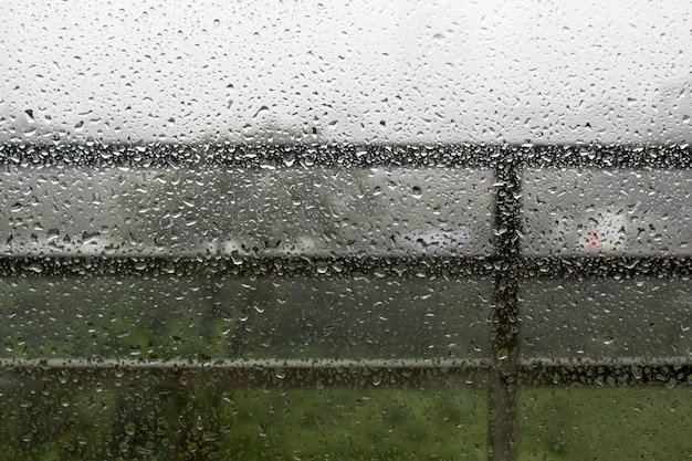 Gouttes de pluie sur la vitre avec une brume blanche sur le fond du balcon