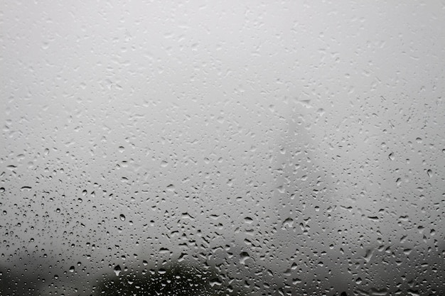 Gouttes de rosée dues à la pluie sur la fenêtre en verre sur fond de brouillard blanc