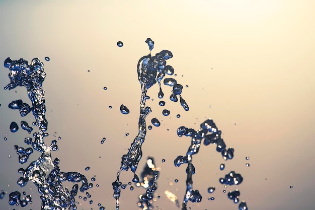 Gouttes volantes de gros plan de fontaine d'eau sur le fond du ciel