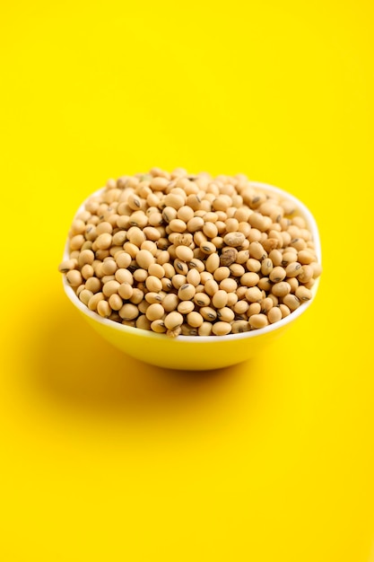 Graine de soja sèche dans un bol sur fond jaune