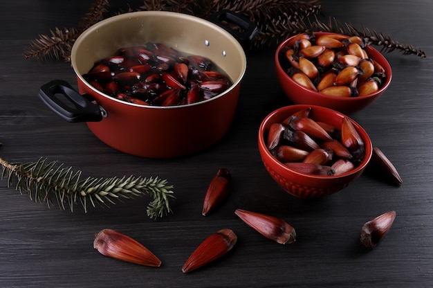 Graines d'araucaria typiques utilisées comme condiment dans la cuisine brésilienne en hiver. Pignons brésiliens dans un bol en bois marron et rouge sur fond de bois gris.