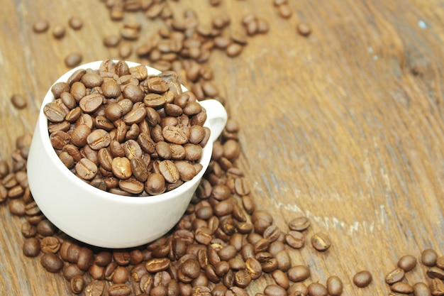 Graines de café en tasse sur fond de bois