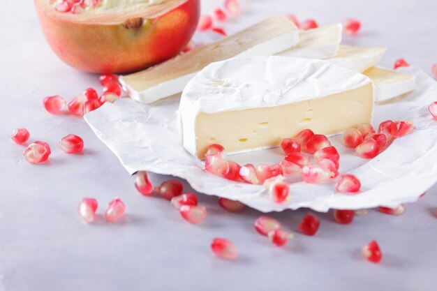 Graines de camembert et de grenade sur papier parchemin sur fond clair Délicieux fromage sur la table en gros plan Un excellent produit pour un petit-déjeuner