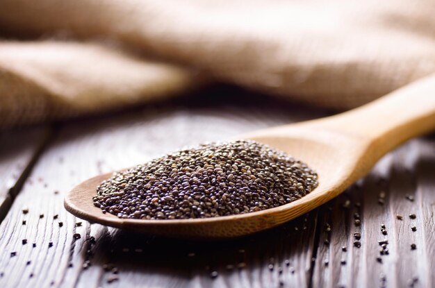 Graines de Chia crues dans une spatule en bambou sur une table en bois