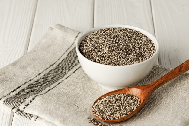 Graines de chia dans un bol avec cuillère en bois sur table en bois