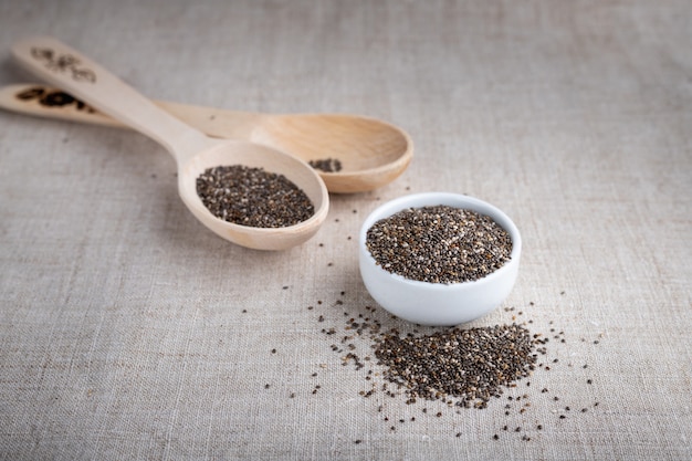 Graines de chia dans un bol et sur une cuillère en bois sur la table