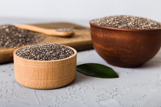 Graines de chia dans un bol et une cuillère sur fond coloré Salvia hispanica saine dans un petit bol Superfood sain