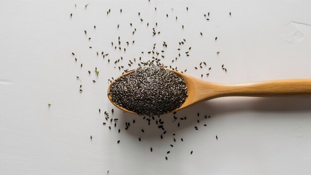 Graines de chia dans une cuillère de bois isolées sur un fond blanc