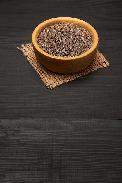 Graines de chia naturelles biologiques dans un bol en bois en gros plan sur fond ou table en bois foncé