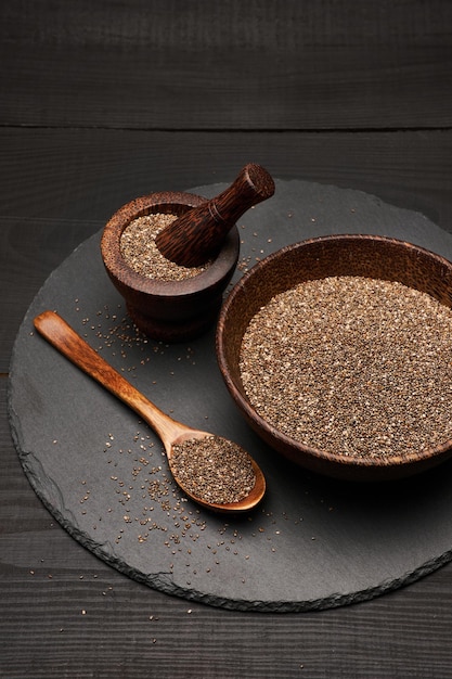 Graines de chia naturelles biologiques dans un bol en bois en gros plan sur fond ou table en bois foncé