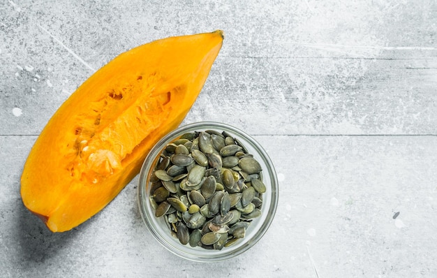 Photo graines de citrouille dans un bol et un morceau de citrouille mûre