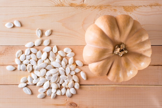 Graines de citrouille non pelées rôties et citrouille sur une table en bois