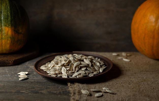 Graines de citrouille sur une plaque brune sur un fond en bois