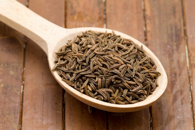 Graines de cumin dans une cuillère en bois