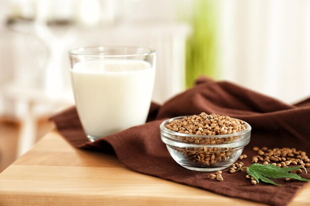 Graines dans un bol et verre avec du lait de chanvre sur table