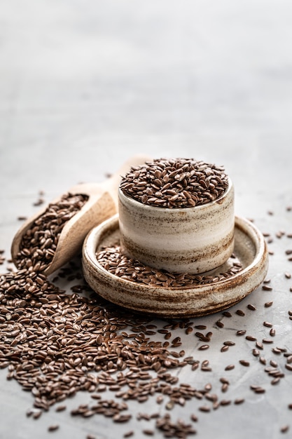 Graines de lin dans un bol en céramique isolé avec une cuillère en bois. Aliments sains biologiques. Photo verticale