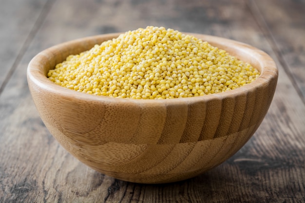 Graines de millet biologiques dans un bol en bois sur une table en bois