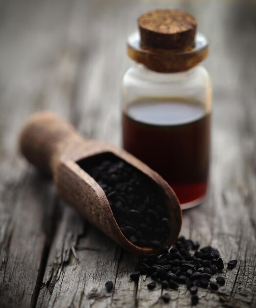 Graines de nigelle et huile essentielle dans une bouteille en verre