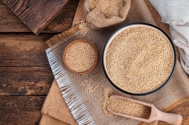 Graines de quinoa blanc dans un bol sur un fond en bois marron vue de dessus copie espace