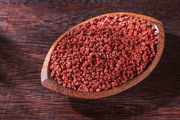 Graines de rocou dans un bol sur fond de bois Bixa Orellana