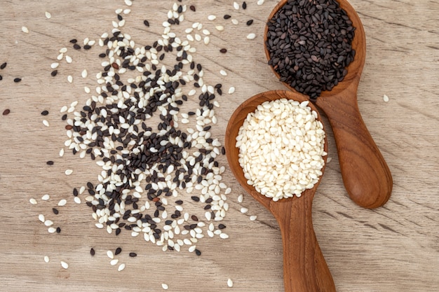 Photo graines de sésame noires et blanches biologiques dans une cuillère en bois, nourriture saine pour réduire la pression artérielle