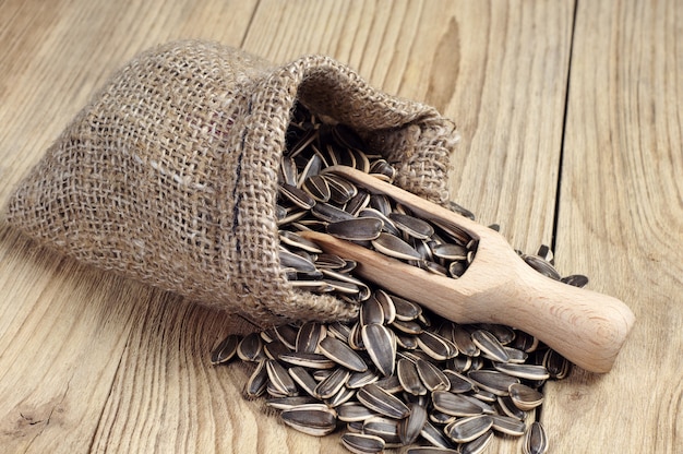 Graines de tournesol dans un sac et une cuillère sur une table en bois