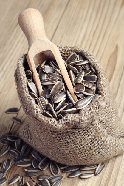 Graines de tournesol dans un sac et une cuillère sur une table en bois