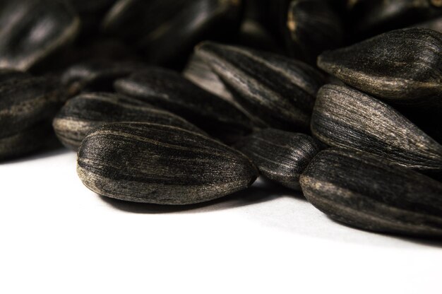Graines de tournesol noir en macro isolé sur fond blanc Photo alimentaire avec gros plan de texture