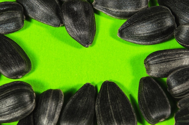 Graines de tournesol noires en macro isolées sur fond vert Photo alimentaire avec gros plan de texture