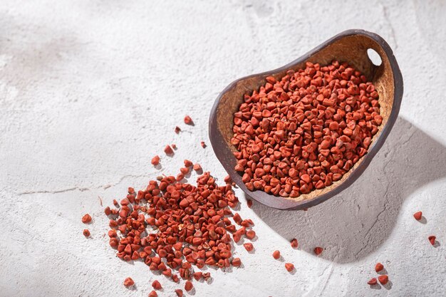 Grains d'achiote dans un bol en bois sur fond blanc Bixa orellana