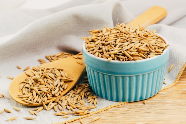 Grains d'avoine crus dans un bol et une cuillère en bois sur la table