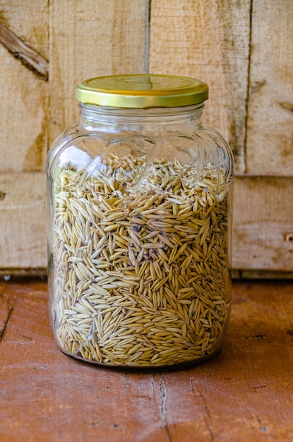 Grains d'avoine dans un bocal en verre sur un fond en bois