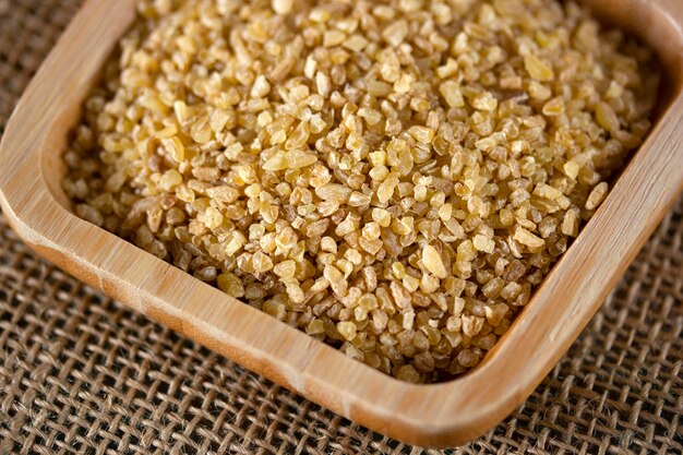 Grains de blé crus dans une assiette en bois