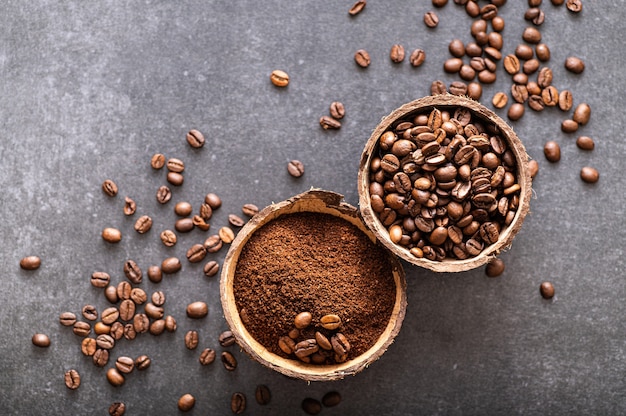 Grains de café arabica noirs fraîchement moulus aromatiques dans un bol de noix de coco, vue de dessus avec place pour le texte