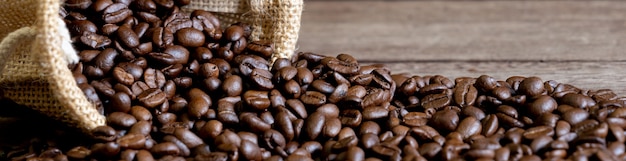 Photo grains de café arabica torréfiés sortant d'une bannière de sac de paille