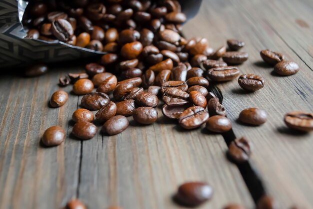 Grains de café Arabica versés hors du sac sur une table en bois