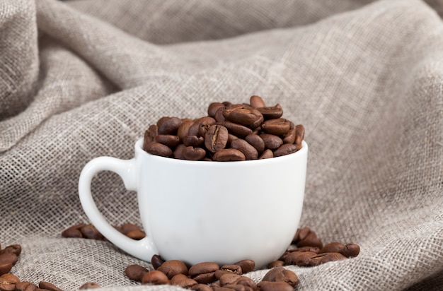 Grains de café aromatiques dans une tasse, grains de café pour faire un délicieux café dans une tasse, grains de café sous une forme entière pour boire, gros plan