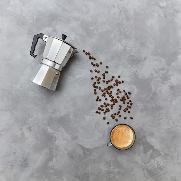 Grains de café aromatiques sous la forme d'une boisson versée d'une cafetière italienne en métal sur fond gris