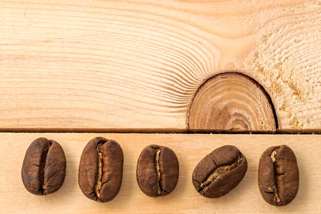 Grains de café bruns sur fond de planche de bois texturé jaune se bouchent.